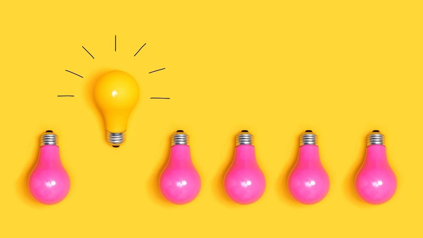 Yellow light bulb standing out from other pink ones