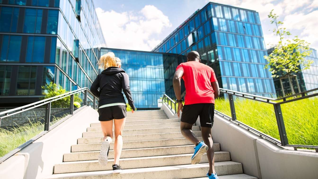 Man and woman running up steps towards office