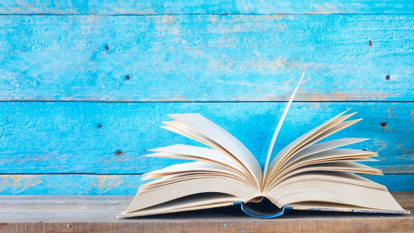 Book open on table with blue wooden background